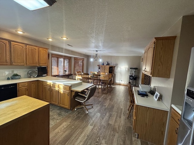 kitchen featuring decorative light fixtures, black dishwasher, a breakfast bar area, dark hardwood / wood-style flooring, and kitchen peninsula