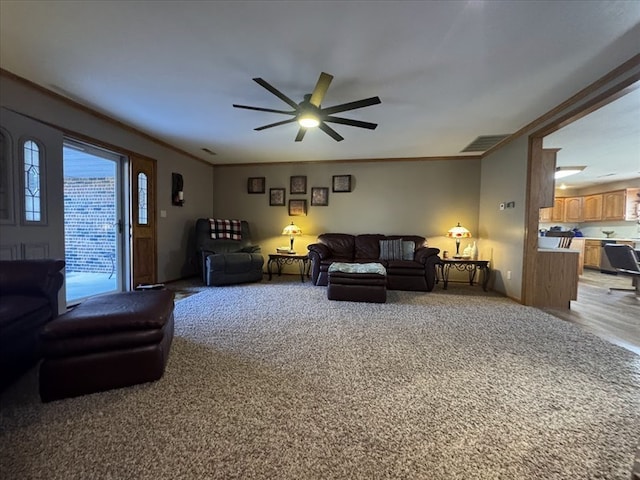 living room featuring crown molding, ceiling fan, and carpet floors