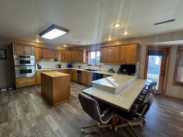 kitchen featuring sink, a kitchen bar, black appliances, dark wood-type flooring, and a textured ceiling