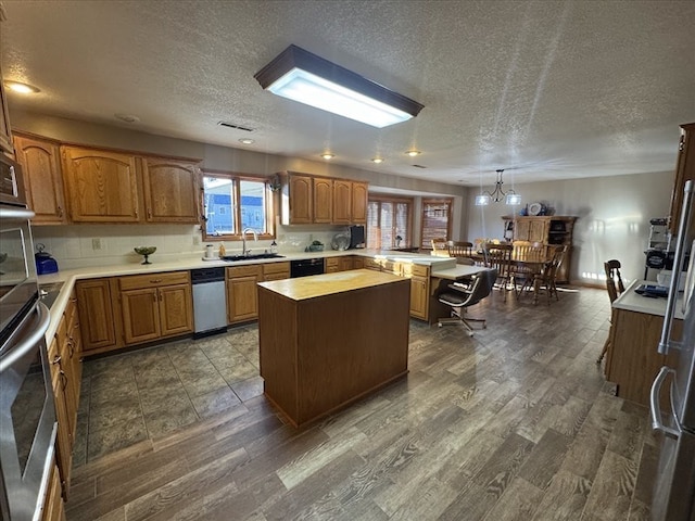 kitchen featuring dark wood-type flooring, decorative light fixtures, sink, and a kitchen island