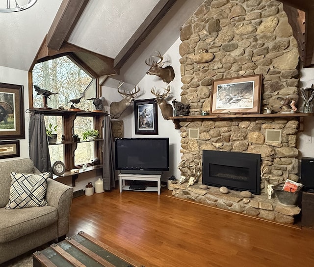 unfurnished living room with hardwood / wood-style floors, vaulted ceiling with beams, and a stone fireplace