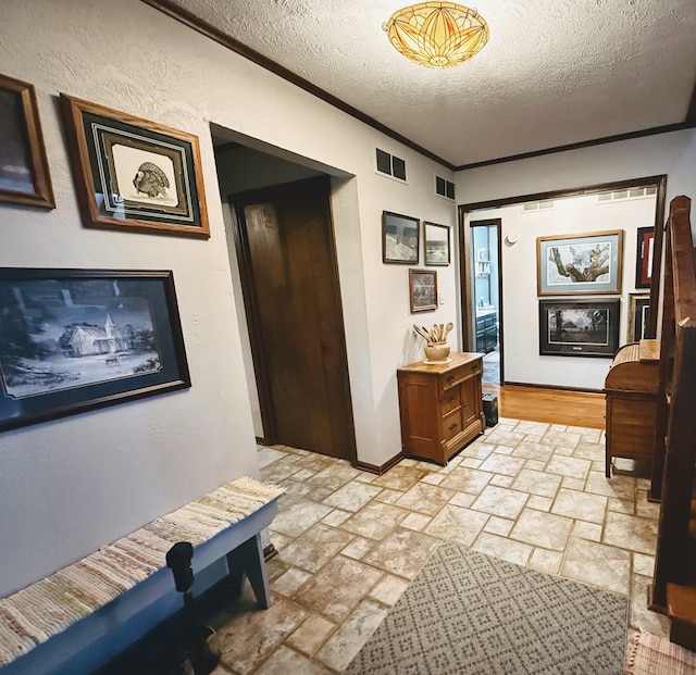 hall with a textured ceiling and ornamental molding