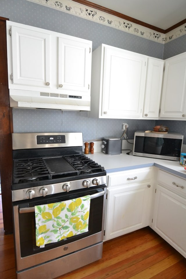 407 E Harrison St, Kirksville, MO 63501 - kitchen with stainless steel appliances, under cabinet range hood, light wood-style floors, white cabinets, and wallpapered walls