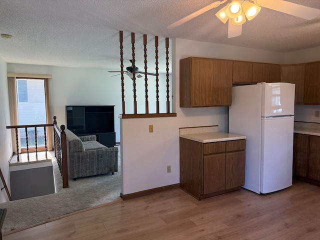 1214 E Washington, Kirksville, MO 63501 - kitchen featuring freestanding refrigerator, ceiling fan, light wood-type flooring, brown cabinetry, and a textured ceiling