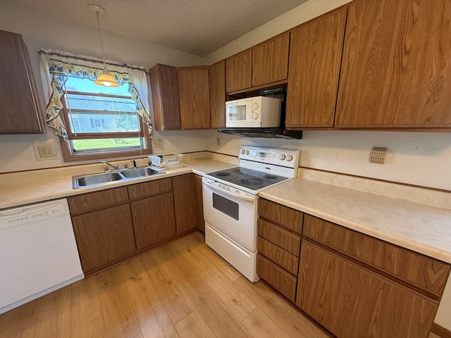 1214 E Washington, Kirksville, MO 63501 - kitchen featuring white appliances, light wood-type flooring, light countertops, brown cabinetry, and a textured ceiling