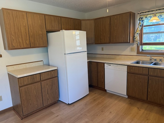 1214 E Washington, Kirksville, MO 63501 - kitchen with white appliances, light countertops, light wood-style flooring, hanging light fixtures, and a textured ceiling