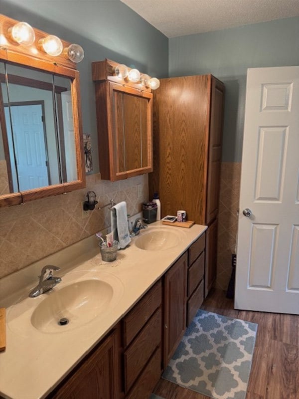 34829 State Highway C, Bevier, MO 63532 - bathroom with double vanity, wood finished floors, a textured ceiling, tile walls, and a wainscoted wall