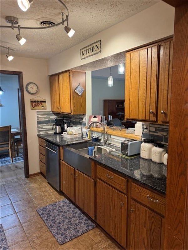34829 State Highway C, Bevier, MO 63532 - kitchen featuring dishwasher, rail lighting, brown cabinets, tasteful backsplash, and a textured ceiling