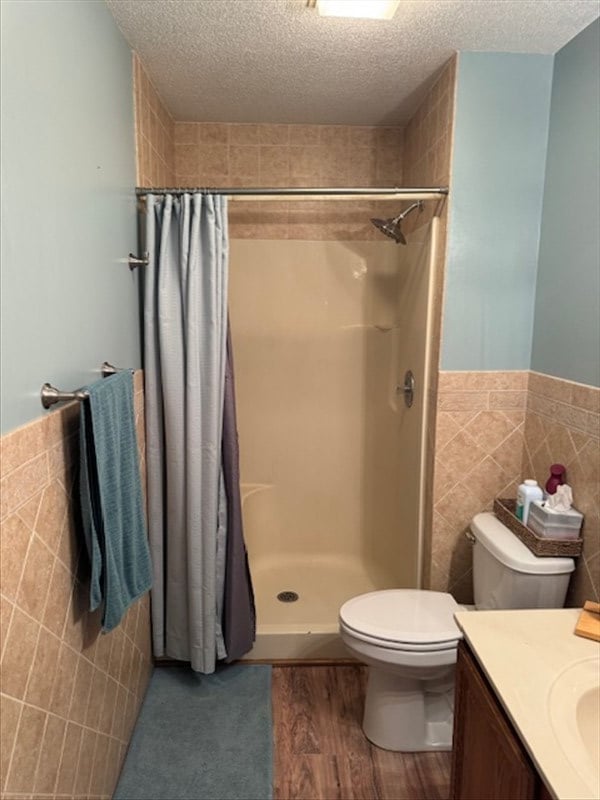 34829 State Highway C, Bevier, MO 63532 - full bathroom featuring tile walls, a textured ceiling, a shower with curtain, vanity, and wainscoting