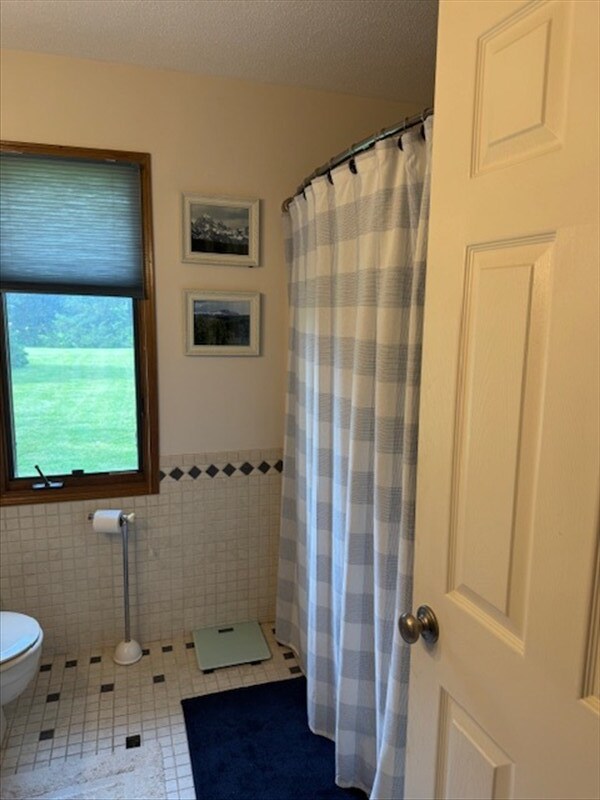 34829 State Highway C, Bevier, MO 63532 - bathroom featuring tile patterned floors, tile walls, curtained shower, and wainscoting