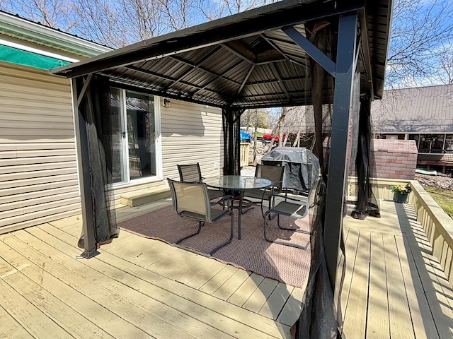 deck with outdoor dining space, a gazebo, and a grill