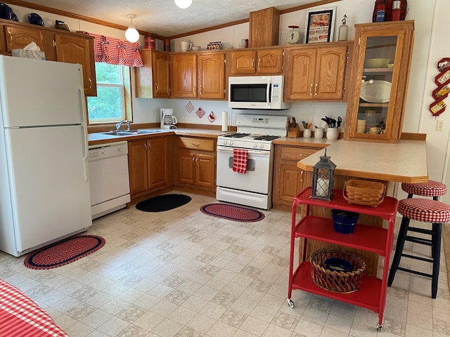 kitchen with crown molding, white appliances, light floors, and brown cabinets