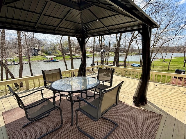 wooden deck with a water view, a gazebo, and outdoor dining space