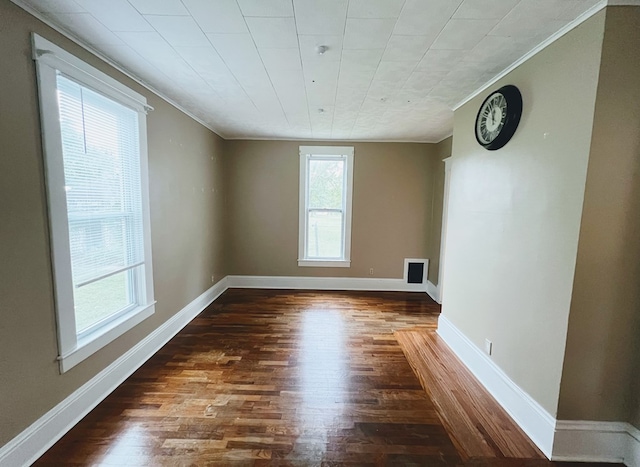 unfurnished room with ornamental molding and dark wood-type flooring