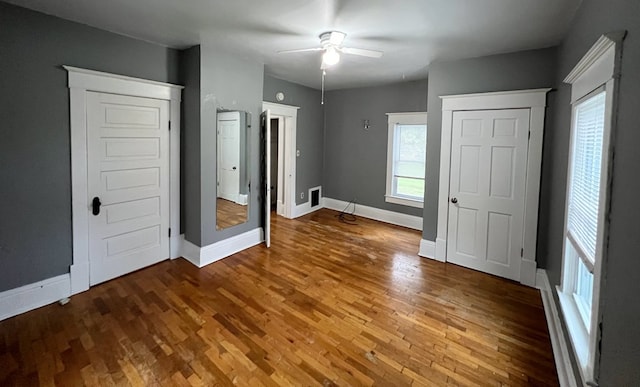 unfurnished bedroom featuring multiple windows, hardwood / wood-style flooring, and ceiling fan