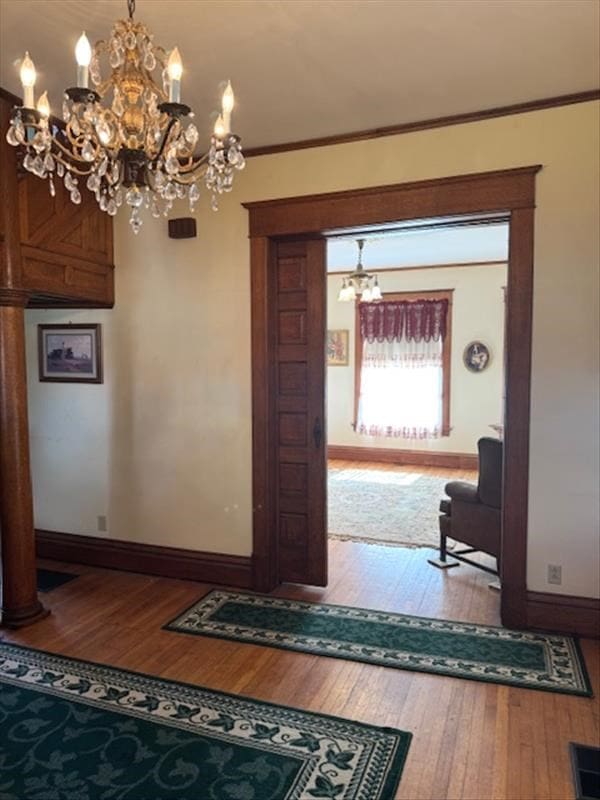 interior space with wood-type flooring, ornamental molding, and a chandelier