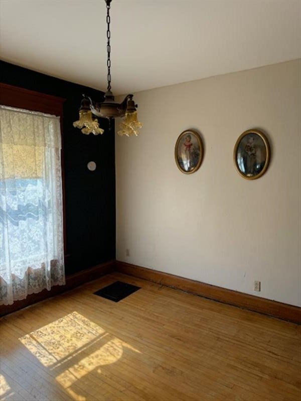 unfurnished dining area with hardwood / wood-style flooring and a notable chandelier