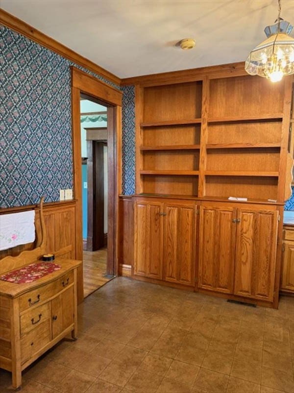 interior space featuring built in shelves, wooden walls, and a chandelier