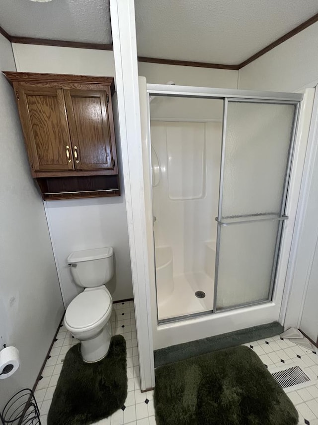 bathroom with toilet, a stall shower, and a textured ceiling