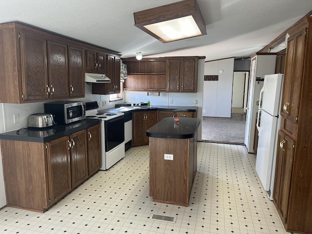 kitchen with white appliances, light floors, under cabinet range hood, dark countertops, and a center island