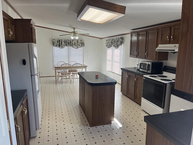 kitchen with dark countertops, white appliances, exhaust hood, crown molding, and light floors