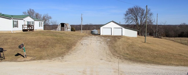 view of yard with a detached garage, an outdoor structure, and driveway