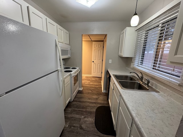 kitchen with hanging light fixtures, white appliances, sink, white cabinetry, and dark hardwood / wood-style floors