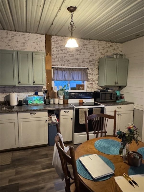 kitchen with dark countertops, stainless steel microwave, dark wood-style flooring, pendant lighting, and range with electric stovetop