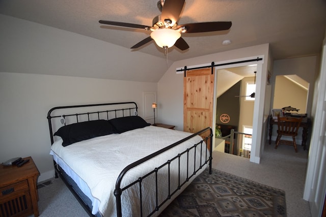 carpeted bedroom featuring ceiling fan, a barn door, and vaulted ceiling