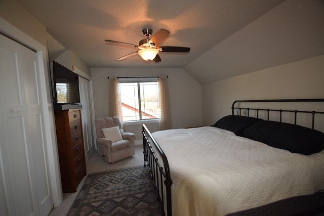 carpeted bedroom featuring ceiling fan, vaulted ceiling, a closet, and a textured ceiling