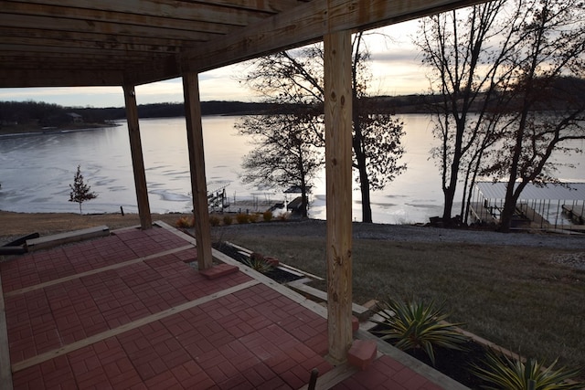 patio terrace at dusk featuring a pergola and a water view