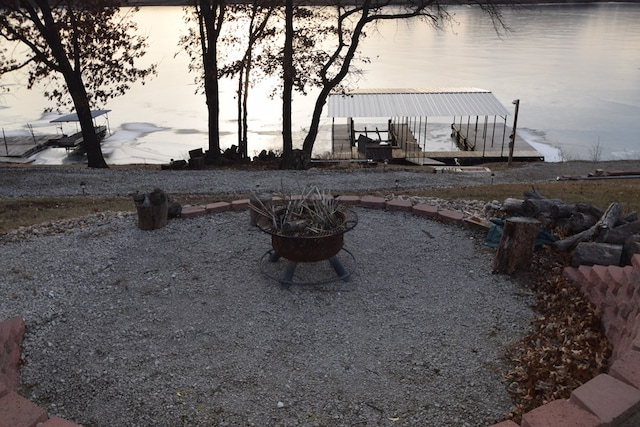 exterior space with a dock, a fire pit, and a water view