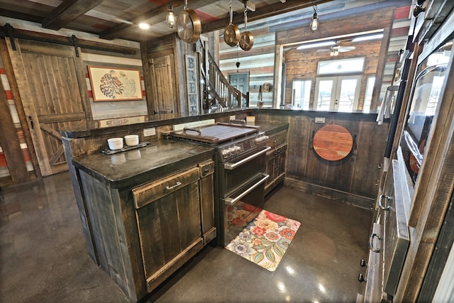 kitchen featuring beam ceiling, french doors, log walls, a barn door, and stainless steel stove