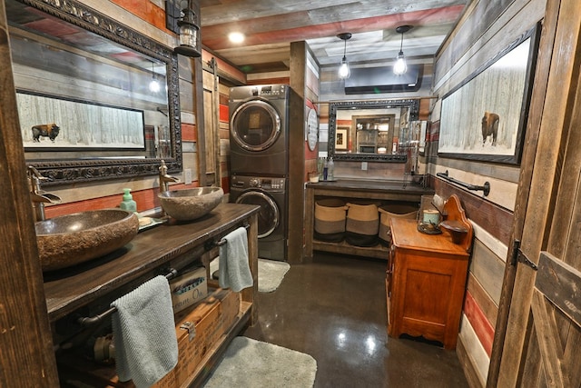 interior space featuring wood walls, stacked washer and dryer, vanity, and concrete flooring