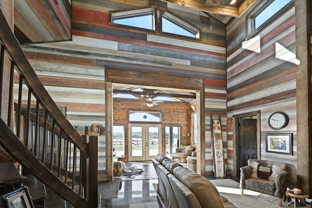 interior space featuring french doors, high vaulted ceiling, ceiling fan, and wood walls