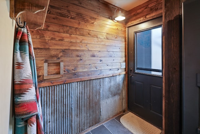 entryway featuring dark tile patterned floors and wood walls