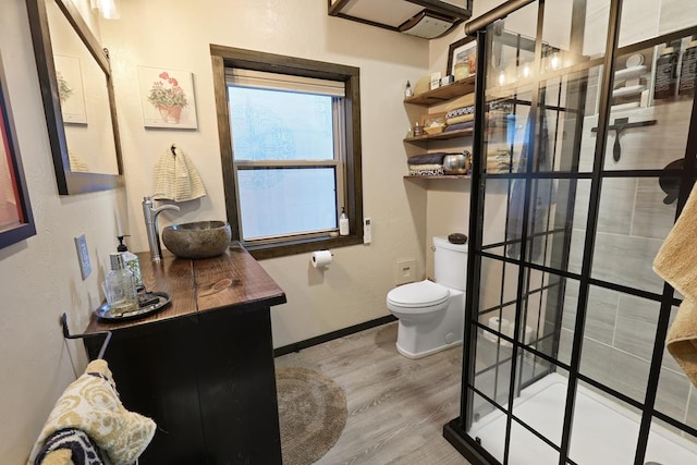 bathroom with hardwood / wood-style floors, vanity, toilet, and walk in shower