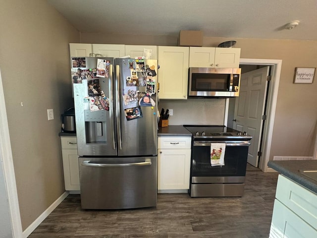 113 Elm St, Milan, MO 63556 - kitchen with appliances with stainless steel finishes, dark countertops, dark wood finished floors, white cabinets, and baseboards