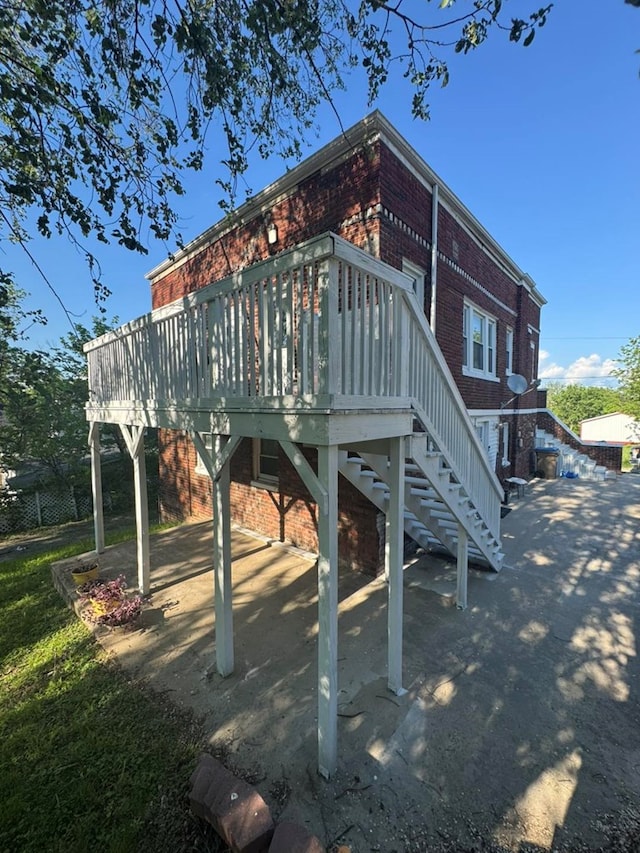 113 Elm St, Milan, MO 63556 - rear view of property featuring brick siding, a deck, and stairway