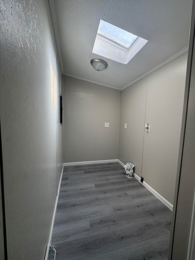 washroom featuring a skylight, wood finished floors, baseboards, and ornamental molding