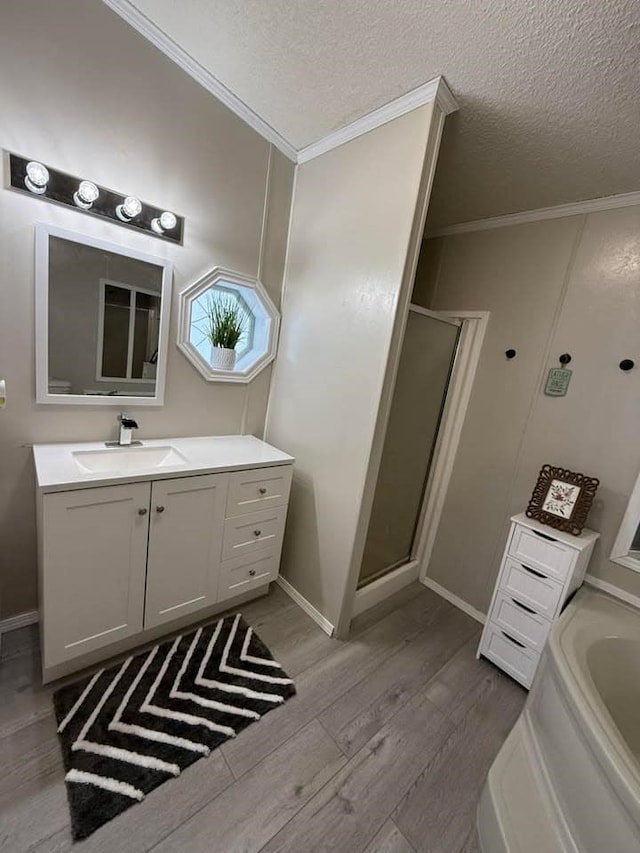 full bath with vanity, wood finished floors, a stall shower, ornamental molding, and a textured ceiling