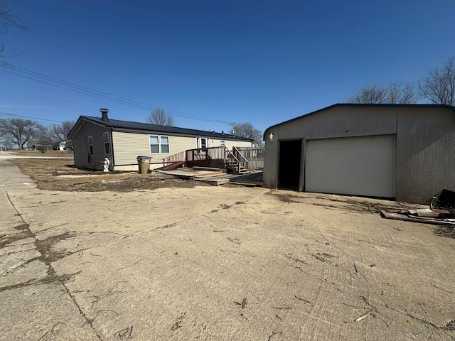 view of property exterior with a detached garage, an outdoor structure, and driveway