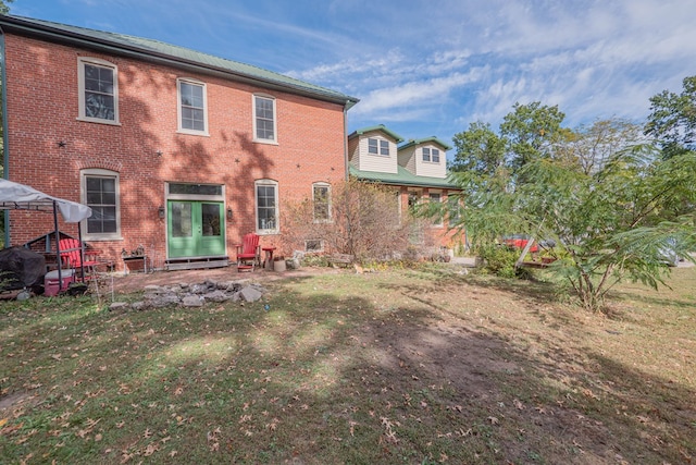 back of property featuring brick siding and a yard