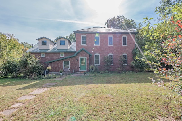 view of front facade with a standing seam roof, a front lawn, metal roof, and brick siding