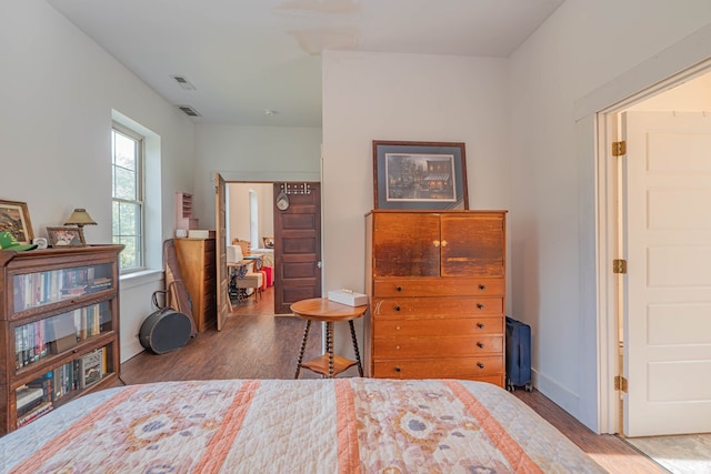 bedroom featuring visible vents, baseboards, and wood finished floors