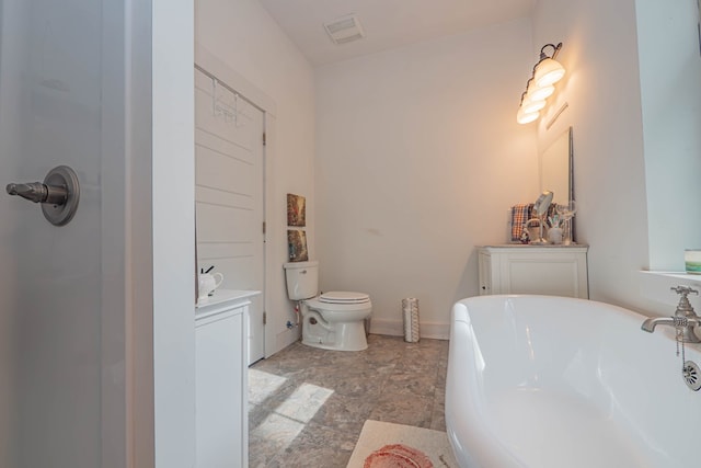 bathroom with baseboards, visible vents, toilet, vanity, and a freestanding tub