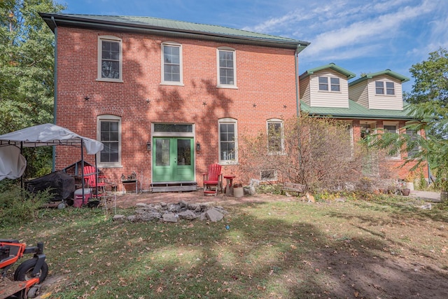 back of property featuring entry steps, a yard, and brick siding