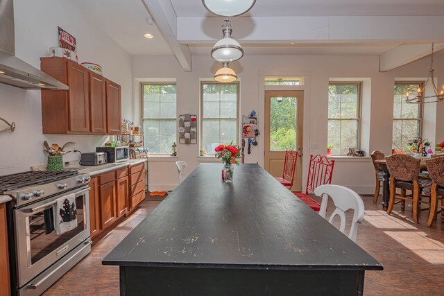 kitchen with appliances with stainless steel finishes, wall chimney range hood, a center island, dark wood-style floors, and brown cabinetry