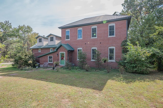 colonial-style house with a front yard, metal roof, and brick siding