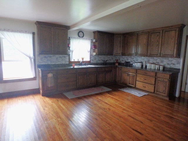 kitchen featuring beam ceiling, backsplash, light hardwood / wood-style floors, and a wealth of natural light